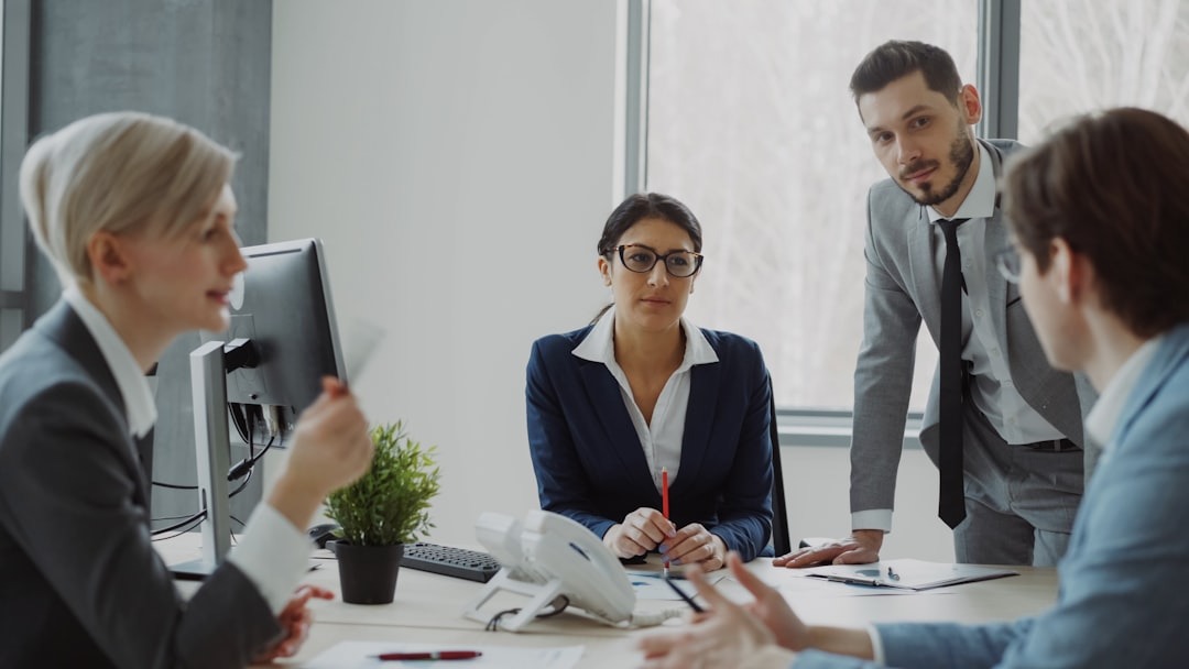 Three professionals in a modern office discussing business at a conference table.